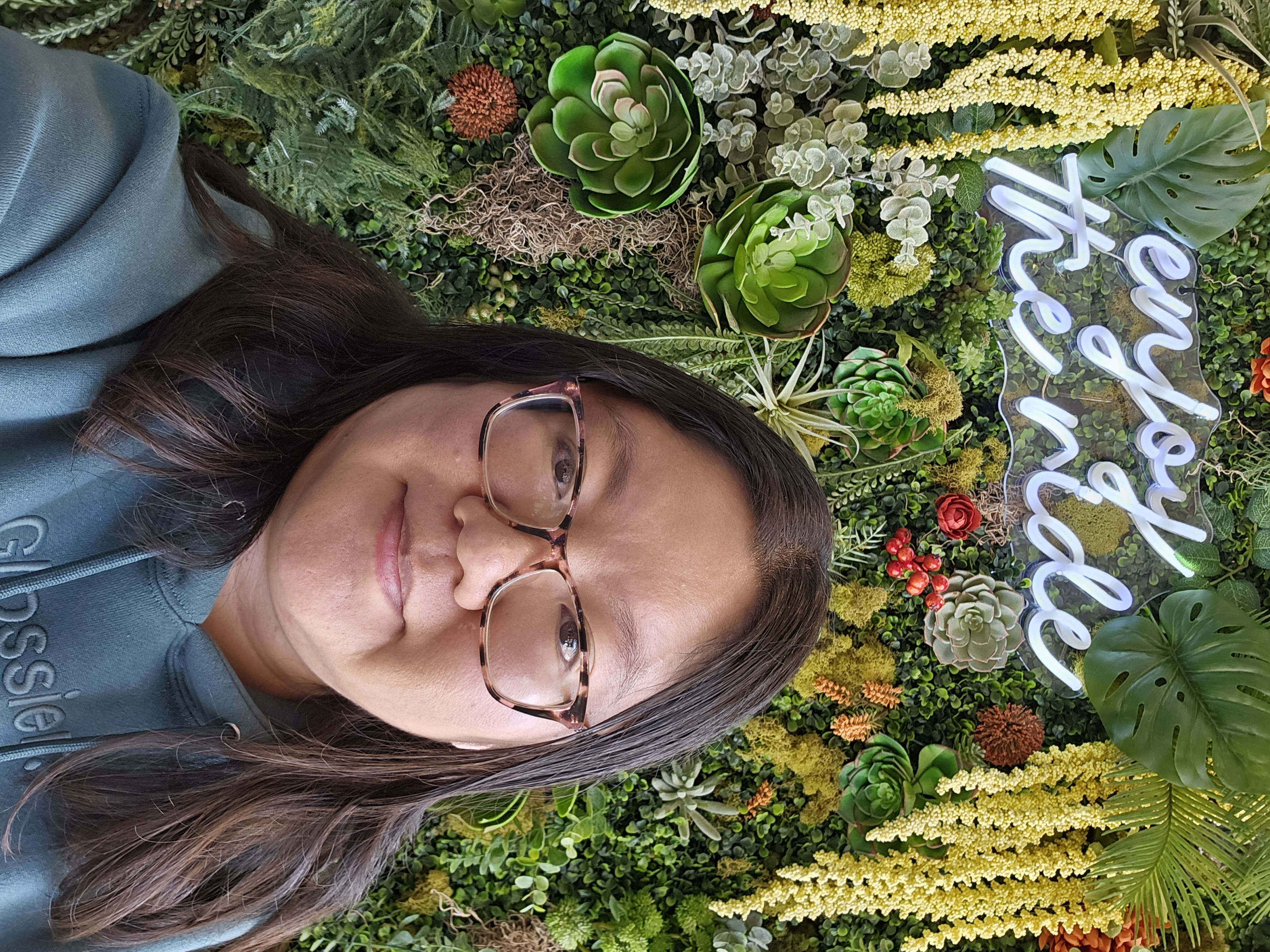 Selfie of Christine taken with a green floral backdrop